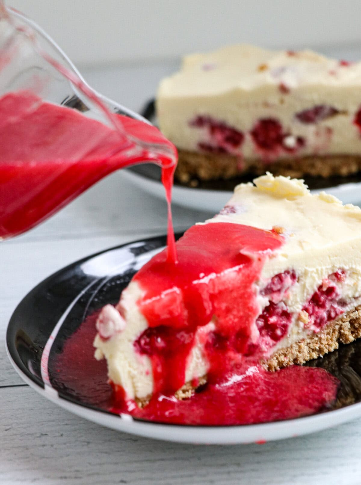 Pouring the raspberry sauce over cheesecake