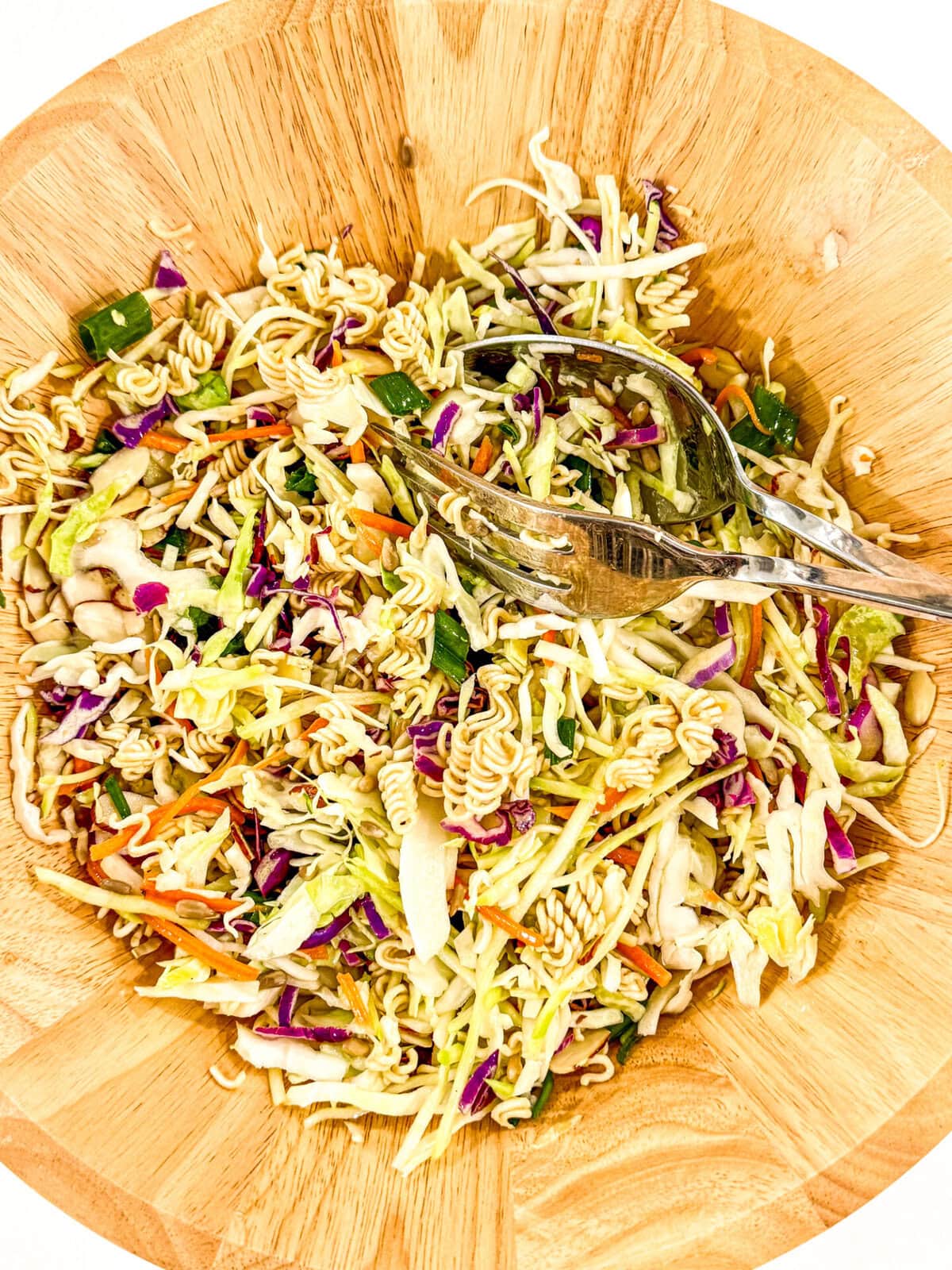 Very easy and tasty salad to make - ramen noodles, almonds and sunflower seeds provide the crunch and the dressing is quite tasty. You can't go wrong with this Oriental (Asian) Coleslaw. Perfect for picnics and potlucks, or any gathering! ramen coleslaw on wooden salad bowl