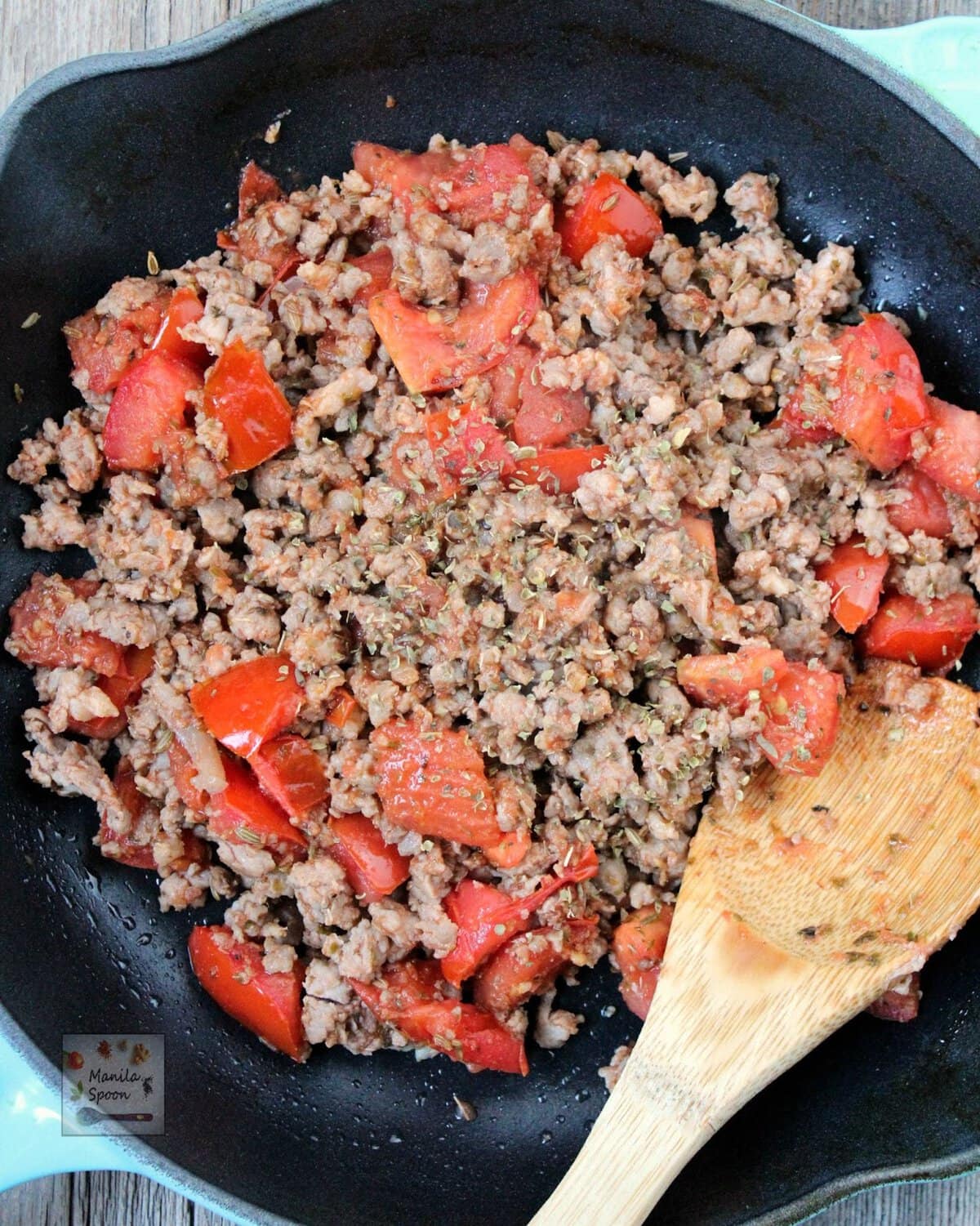 When the meat looks nice and brown already, add the dried oregano and tomatoes. Stir and let the tomatoes soften a little.