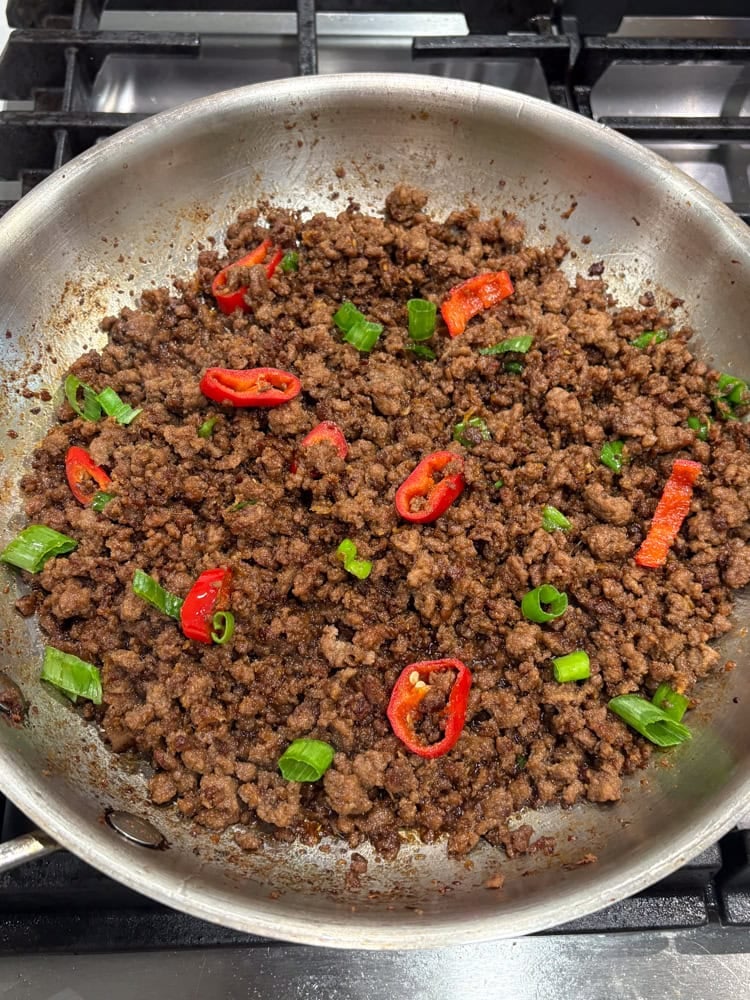 adding red chili pepper and green onions.
