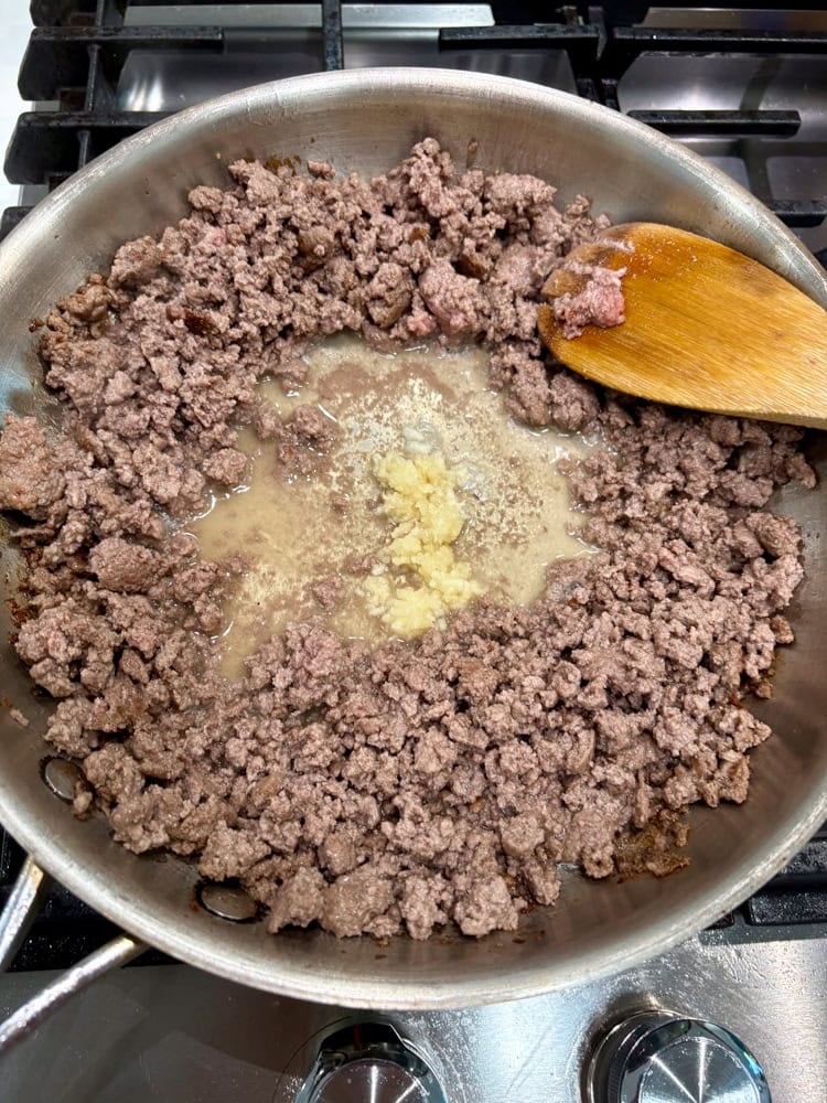 Adding garlic to the sauteed beef.