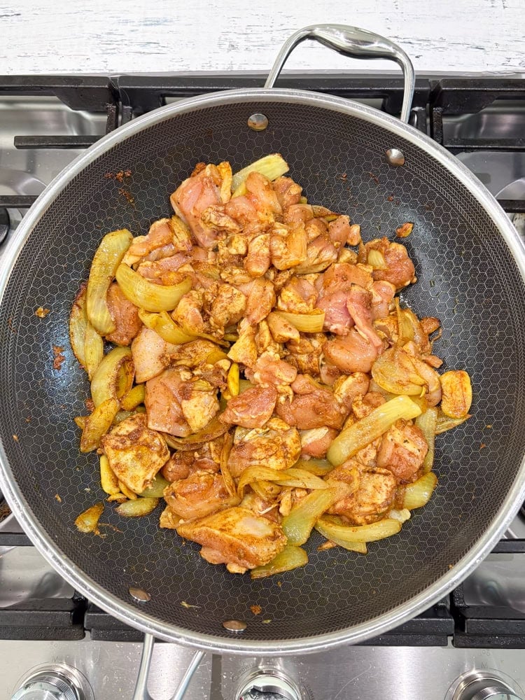Let the spices sizzle for a few seconds, then add the chicken and coat with the spices.