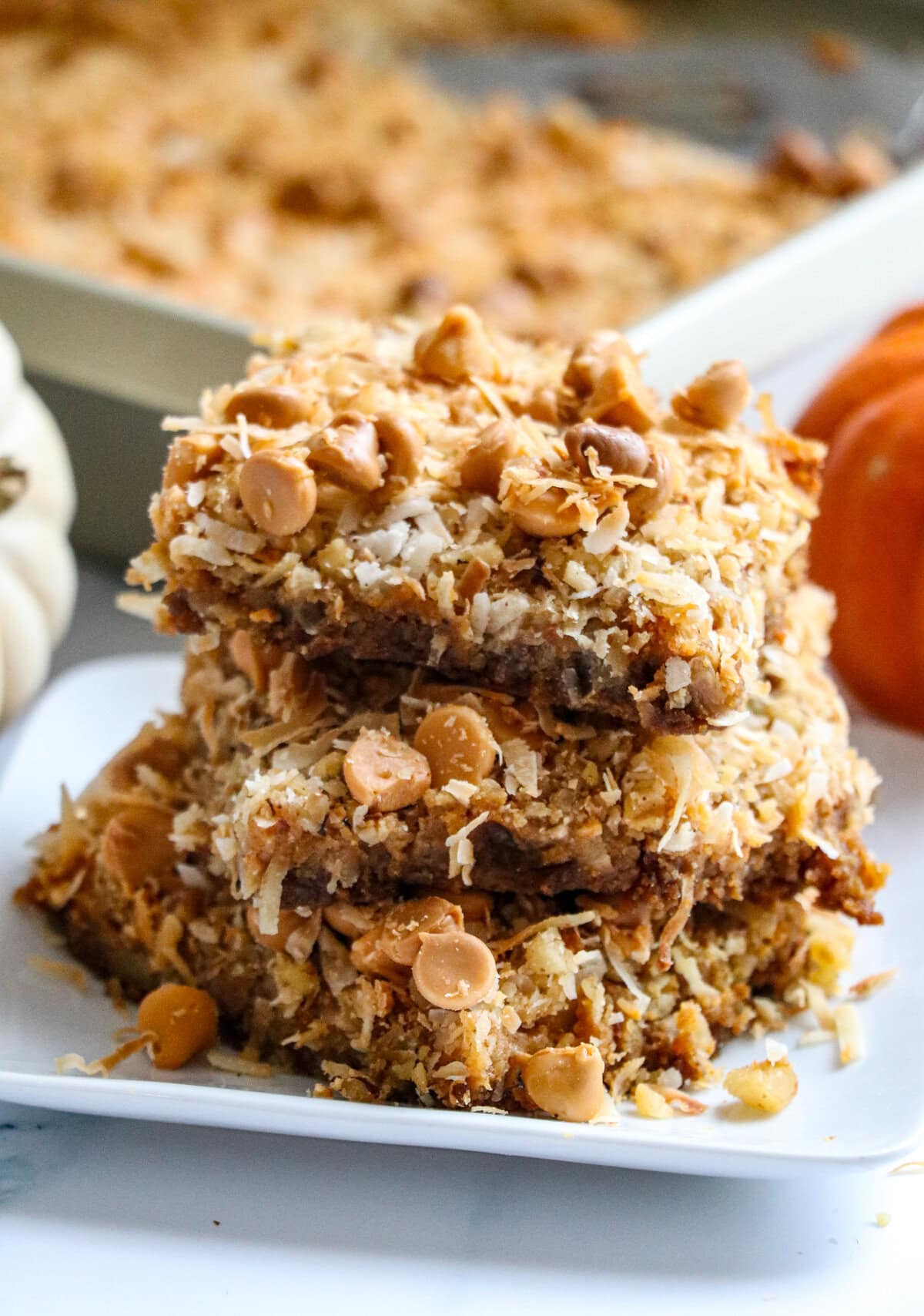 The classic favorite magic bars get a fall-inspired make-over with the addition of pumpkin puree and pumpkin pie spice in these Easy Magic Pumpkin Bars. So yummy and most of all crazy easy to make! 7 layers of deliciousness with every bite of this scrumptious fall dessert! The classic magic bar with a fall makeover: pumpkin magic Bars!