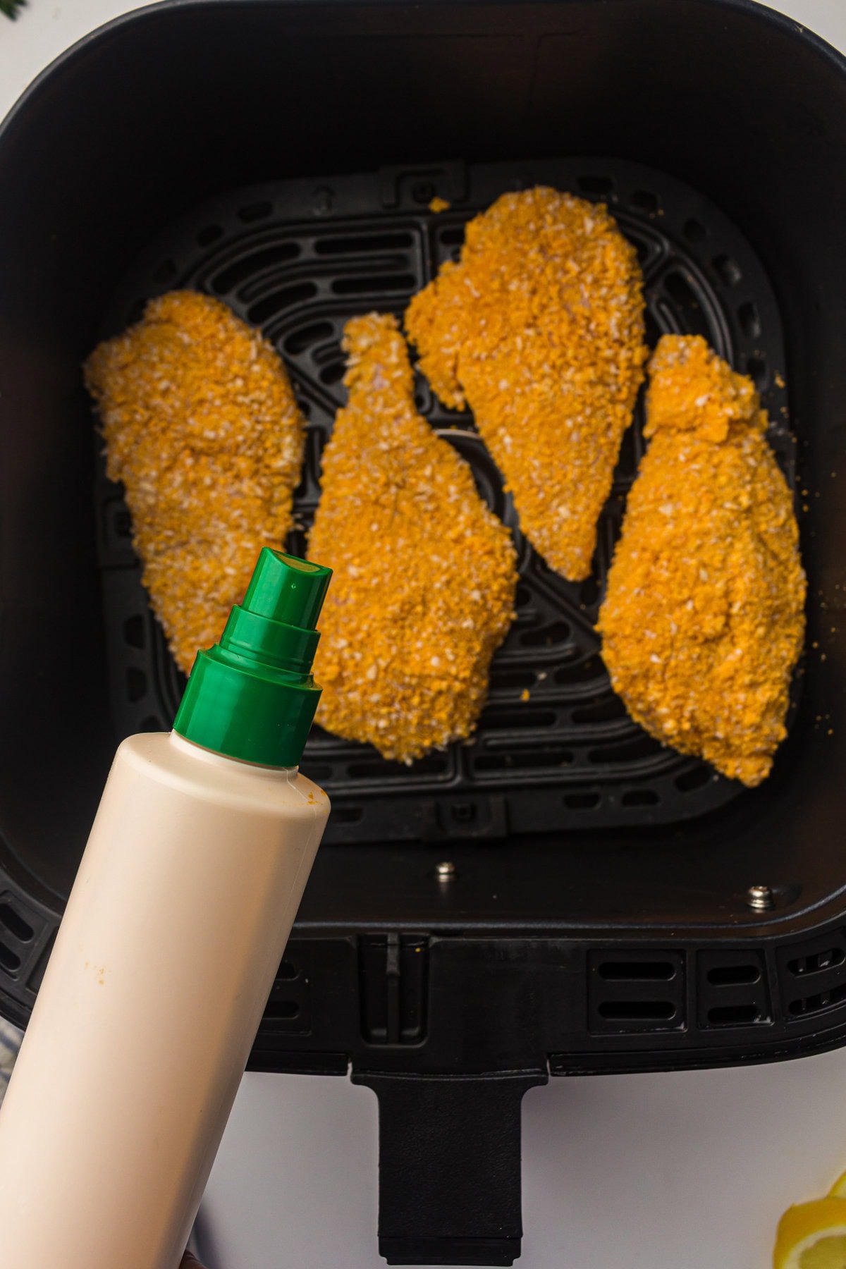 spraying chicken cutlets with oil