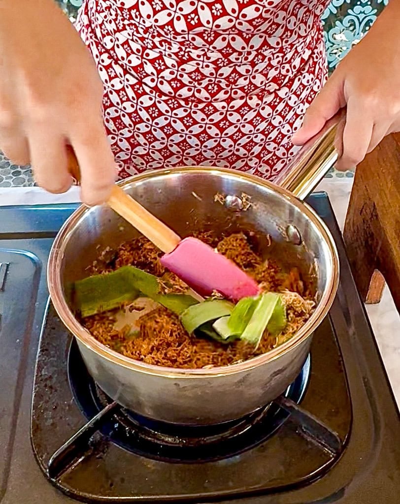 mixing of coconut and palm sugar with pandan leaf over low heat