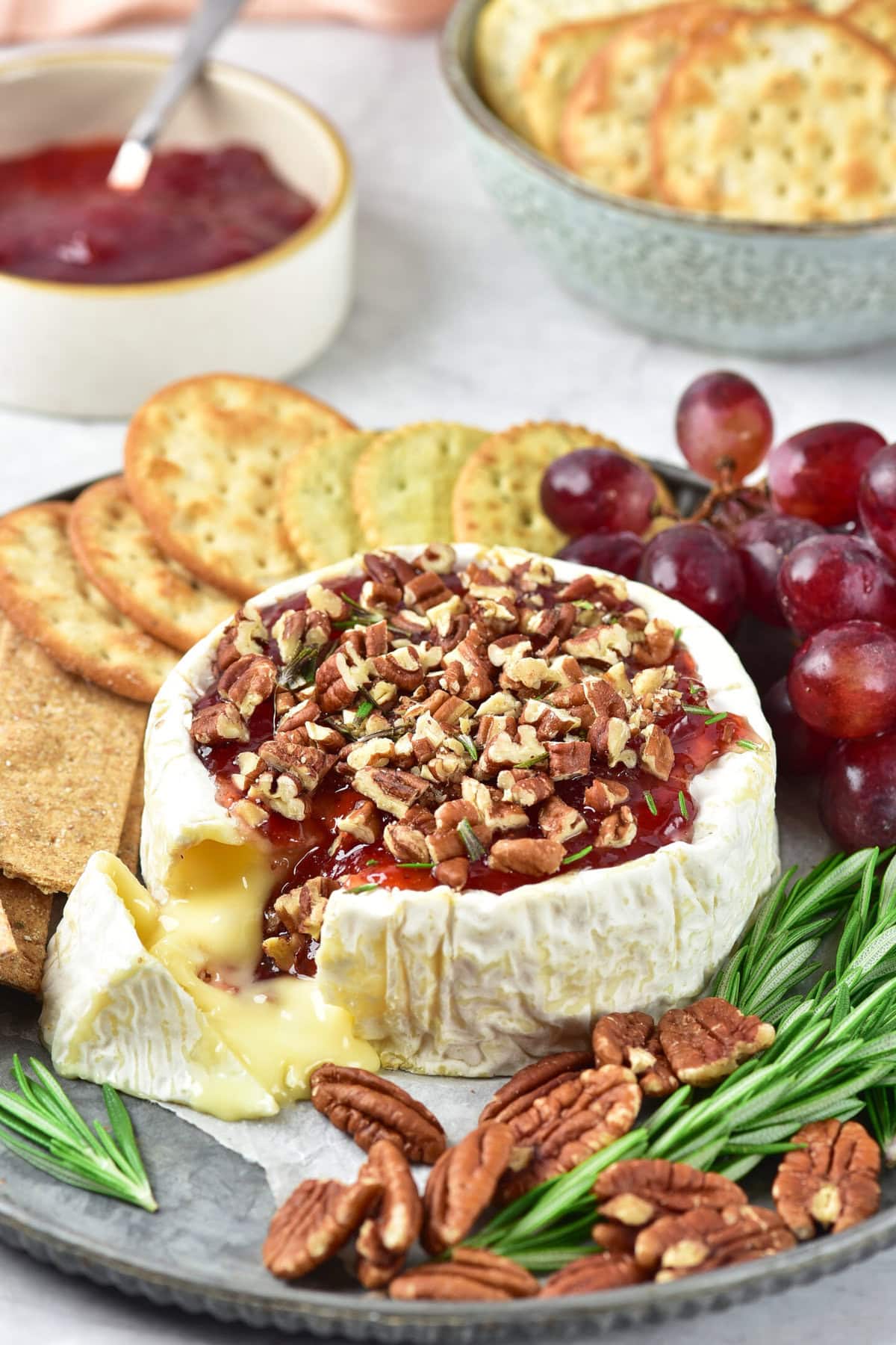 Baked brie with jam is the ultimate easy holiday appetizer—creamy, gooey cheese topped with maple syrup, pecans and cranberry, cherry or jam of your choice. Perfect for Christmas parties, Thanksgiving gatherings, and New Year’s Eve, this simple baked brie recipe comes together in minutes and always impresses. Save this easy party snack to your holiday appetizer board for a crowd-pleasing, make-ahead entertaining idea.