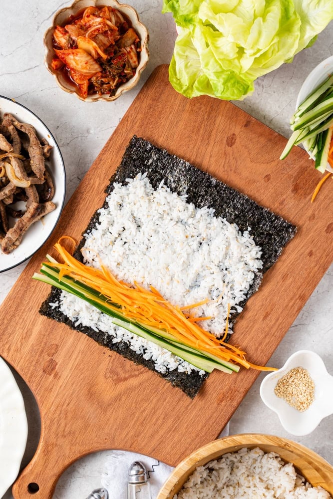Spread about ¾ cup of seasoned rice evenly over the seaweed, leaving about 1 inch uncovered at the top edge.